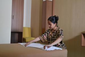 une femme met des serviettes sur un lit dans l'établissement Roemah Canting Homestay, à Yogyakarta