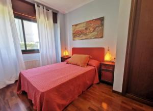 um quarto com uma cama vermelha e duas mesas de cabeceira em P° Olmos, Panxón, bajo con jardín privado em Nigrán