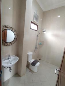 a bathroom with a sink and a toilet and a mirror at Djembar Inn in Kalasan
