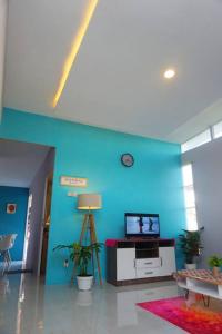 a living room with a blue wall and a tv at Kembang Homestay Yogyakarta in Seturan