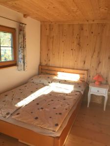 a bed in a room with a wooden wall at Tiny Home am Bach in Pettenbach