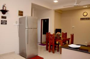 a kitchen with a refrigerator and a table with chairs at Square One CONDO - Kelaniya in Kiribathgoda