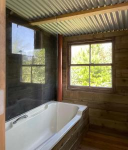 a white bath tub in a room with two windows at The Quarry Caravan in Falmouth
