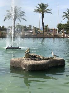 a fountain with a statue in the water with a bird at nice apartment near the park in Torrevieja