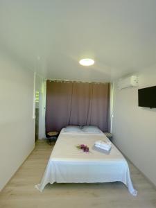 - une chambre avec un lit blanc orné de fleurs dans l'établissement Temana Airport Faa'a,Tahiti, à Fa'a'ā