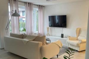un soggiorno con divano, 2 sedie e TV di Ferienwohnung Bullaku a Piding