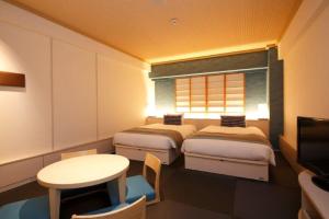um quarto com duas camas e uma mesa e uma televisão em Loisir Hotel Naha em Naha