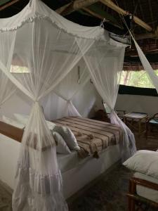 a bedroom with a canopy bed with mosquito nets at Lemara Eco Camp in Kisaki