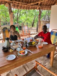 Un uomo e una donna seduti a un tavolo con del cibo di Lemara Eco Camp a Kisaki