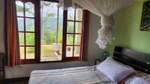 a bedroom with a bed in front of a window at SunnySide Lodge - Tea Plantation Bungalow in Ella