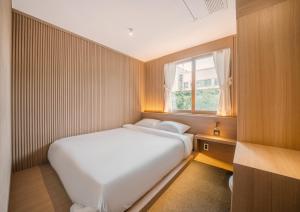 um pequeno quarto com uma cama branca e uma janela em UH Suite Gyeongju em Gyeongju