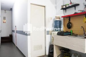 a door in a kitchen with a counter and a sink at Cosmo Harmoni RedPartner in Jakarta