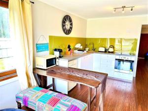 une cuisine avec une table et un four micro-ondes. dans l'établissement Beachfront Holiday Home, à Apollo Bay