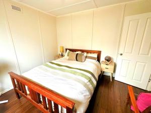 - une chambre avec un grand lit et un cadre en bois dans l'établissement Beachfront Holiday Home, à Apollo Bay