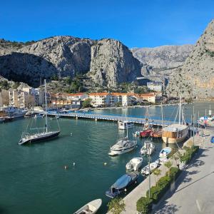 a group of boats docked in a harbor with mountains at Apartman River Breeze in Omiš