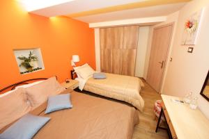 Dos camas en una habitación con paredes naranjas. en Villa Makrades 2, en Paleokastritsa