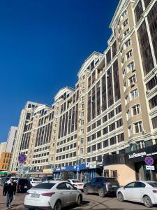 un gran edificio con coches estacionados frente a él en Apartment Olymp Palace at left coast in Astana, en Taldykolʼ