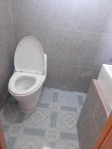 a bathroom with a toilet and a tiled floor at Balai Mariacaria Pension House in Guindulman