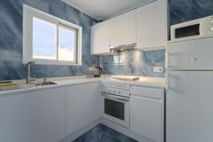 uma cozinha branca com um lavatório e um frigorífico em All Suite Ibiza Aparthotel em San Antonio