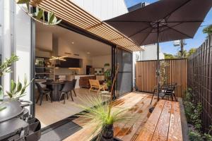 an outdoor patio with a table and an umbrella at Park Place Luxe - Stylish & Central Apartment in Ocean Grove