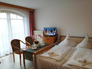 WeidingにあるHotel Lugerhofのベッド2台、テーブル、テレビが備わる客室です。