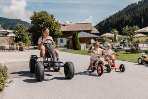 a group of children riding on tricycles down a road at Hofgut Wagrain Apartment & Lifestyle Resort in Wagrain