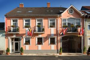 une maison rose avec des drapeaux à l'avant dans l'établissement Hotel Isabell Győr, à Győr