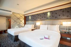 Hotel Dion في تايتشونغ: غرفة فندقية تحتوي على سريرين ومصباحين