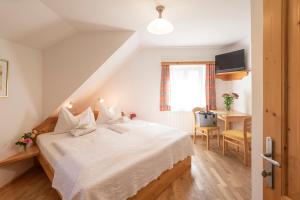 1 dormitorio con cama blanca, escritorio y ventana en Gasthof Pension Orthofer, en Sankt Jakob im Walde