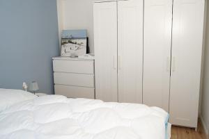 a bedroom with white cabinets and a white bed at Ferienwohnung mit neuer Küche u Bad - W-LAN in Damp