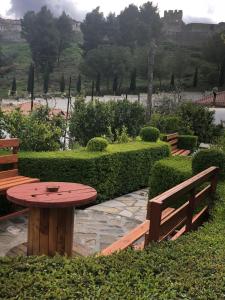 a picnic table and benches in a garden with a lake at Guesthouse Emiljano in Berat