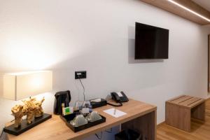 a room with a desk with a television on a wall at Boutique hôtel Corbetta in Les Paccots