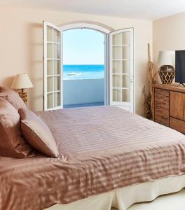 Pieds dans l'eau, villa de luxe 4 chambres في راماتويل: غرفة نوم بسرير كبير مطلة على المحيط