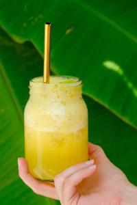 a person holding a jar of orange juice with a straw at OASIA - Boutique Surf House (ADULTS ONLY) in Weligama