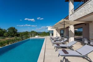 a swimming pool with lounge chairs and umbrellas at Villa Faloniga by Villas Holiday in Vranje Selo