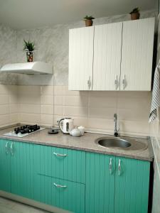 uma cozinha com armários azuis e um lavatório em Уютная 2 ком-я квартира в центре города, район "Арбата" em Almaty