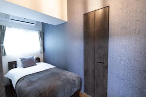 a small bedroom with a bed and a wooden cabinet at Ocean Shinsaibashi in Osaka +55 photos