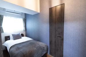 een kleine slaapkamer met een bed en een houten kast bij Ocean Shinsaibashi in Osaka