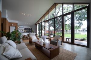 un soggiorno con mobili bianchi e ampie finestre di Nutnicha river house a Lam Phaya