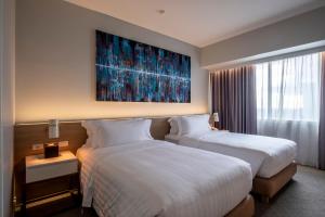 a hotel room with two beds and a painting on the wall at Brittany Hotel BGC in Manila
