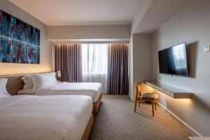 a hotel room with two beds and a flat screen tv at Brittany Hotel BGC in Manila