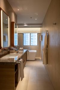 a bathroom with a tub and a sink and a bath tub at Brittany Hotel BGC in Manila