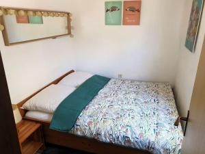 ブライニッセにあるWelkom in DeKreek V59, dem freundlichen Ferienhausの小さなベッドルーム(緑の毛布付きのベッド付)