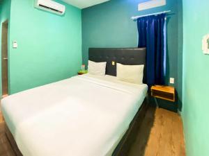 um quarto com uma grande cama branca e uma parede azul em Sentosa Jaya Guest House near RS Hermina Medan RedPartner em Medan