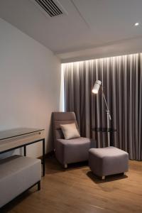 a waiting room with a chair and a desk and a lamp at Brittany Hotel BGC in Manila