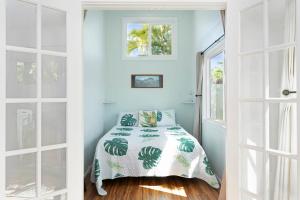 a bedroom with a bed with a green and white comforter at Stylish 1-Bedroom Apartment with AC Just Moments from Kailua Beach in Kailua