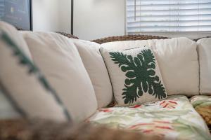 a white couch with white pillows on it at Stylish 1BR Apartment with AC Full Kitchen & WD - Just Steps to the Beach in Kailua