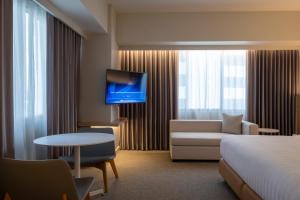 a hotel room with a bed and a couch and a tv at Brittany Hotel BGC in Manila