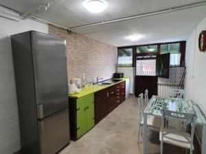 cocina con nevera de acero inoxidable y mesa en vivienda vacacional con jardín y barbacoa, en Cangas de Onís