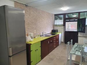 cocina con nevera de acero inoxidable y mesa en vivienda vacacional con jardín y barbacoa, en Cangas de Onís